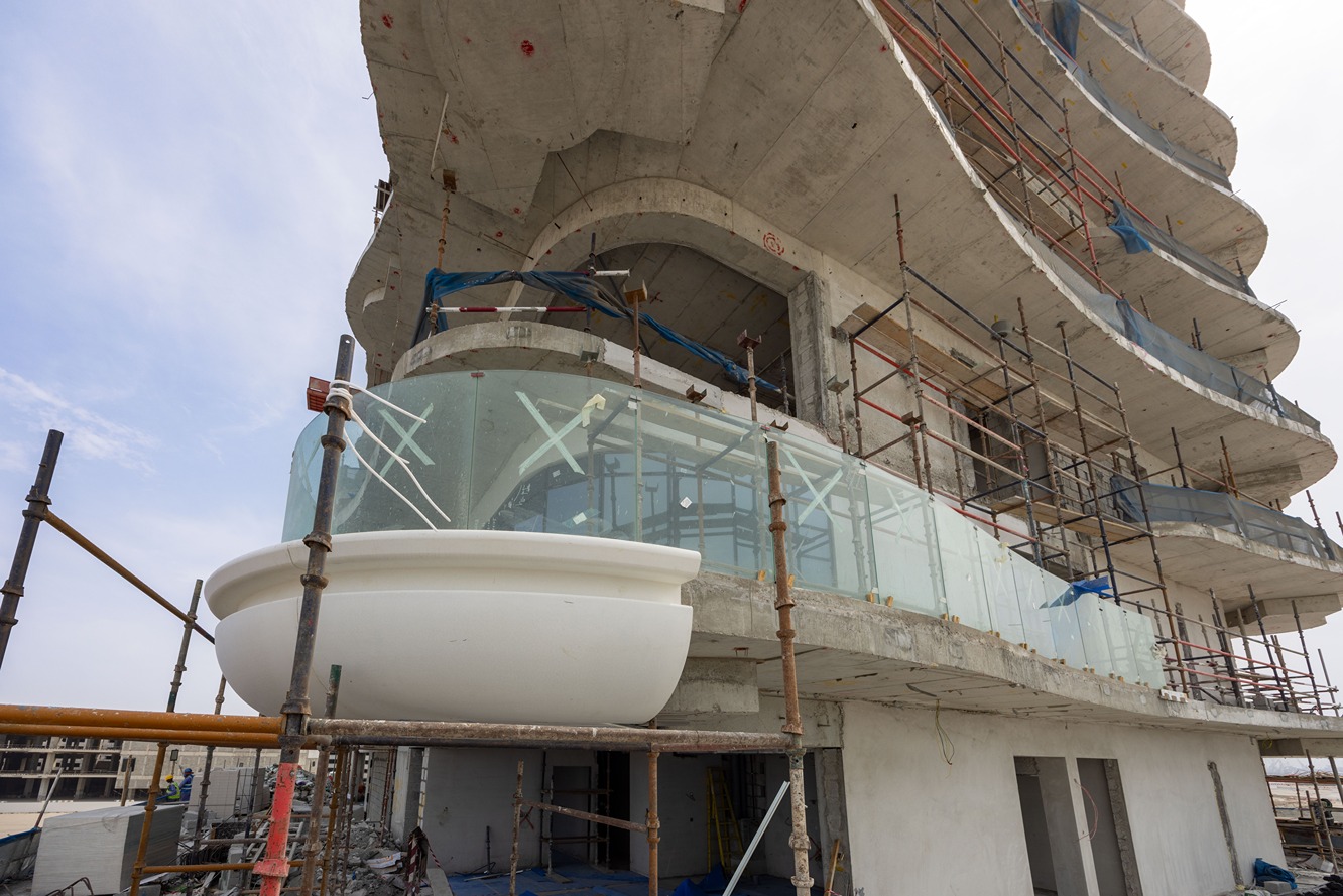 Beach Walk Residence A partially constructed building featuring a curving facade, scaffolding, and a large white bowl-shaped element.